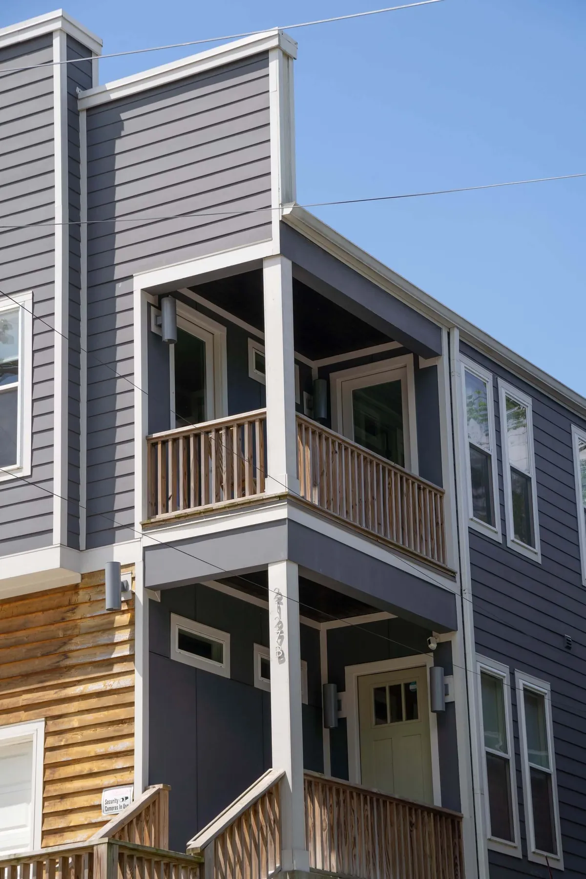 A welcoming exterior balcony and entrance door framed by a wooden railing and windows, suggesting a space to enjoy the evening air or morning coffee before or after a night out.