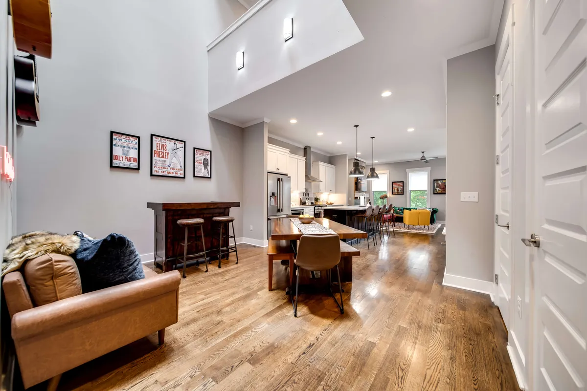 An open-plan living and dining space showcasing a comfortable sofa, modern dining table, kitchen island, and colorful artwork on the walls. The ambiance is both inviting and sophisticated, ideal for entertaining or relaxing between explorations of the city.